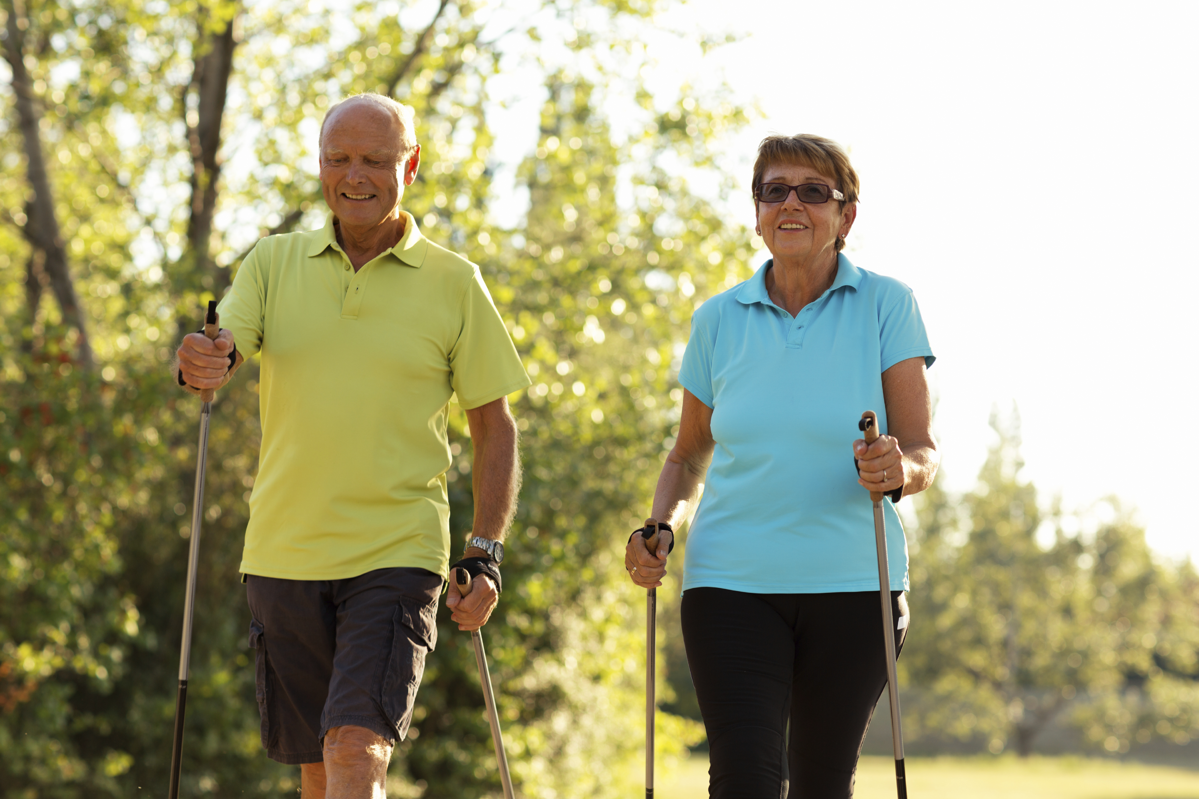 Two active seniors nordic walking outdoors.