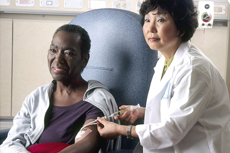 A nurse administers chemotherapy to a patient through a catheter.