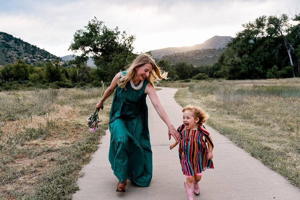 Mother and daughter running through a meadow and laughing.