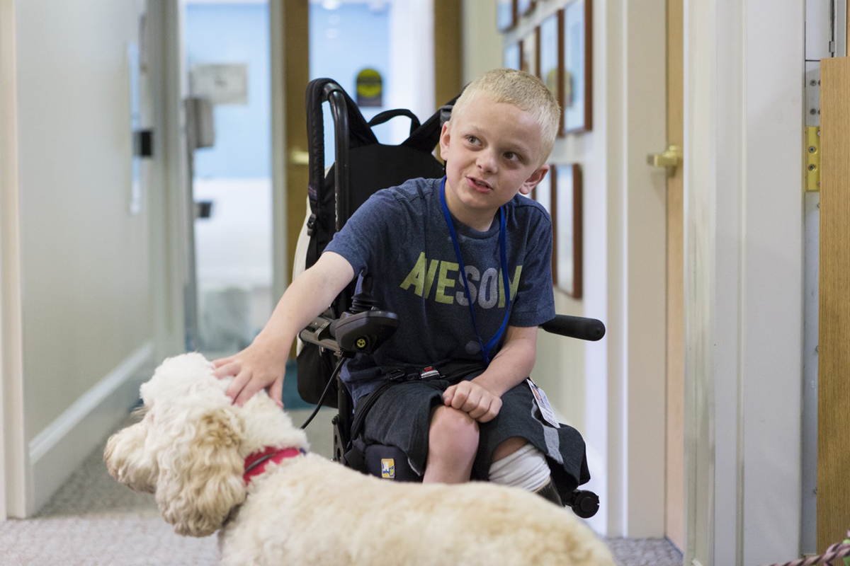 9 year old who received treatment for neurofibromatosis type 1 (NF1) in a phase II clinical trial run by NCI is petting a dog.