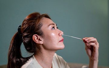 Woman swabs her own nose for an at-home COVID-19 test.