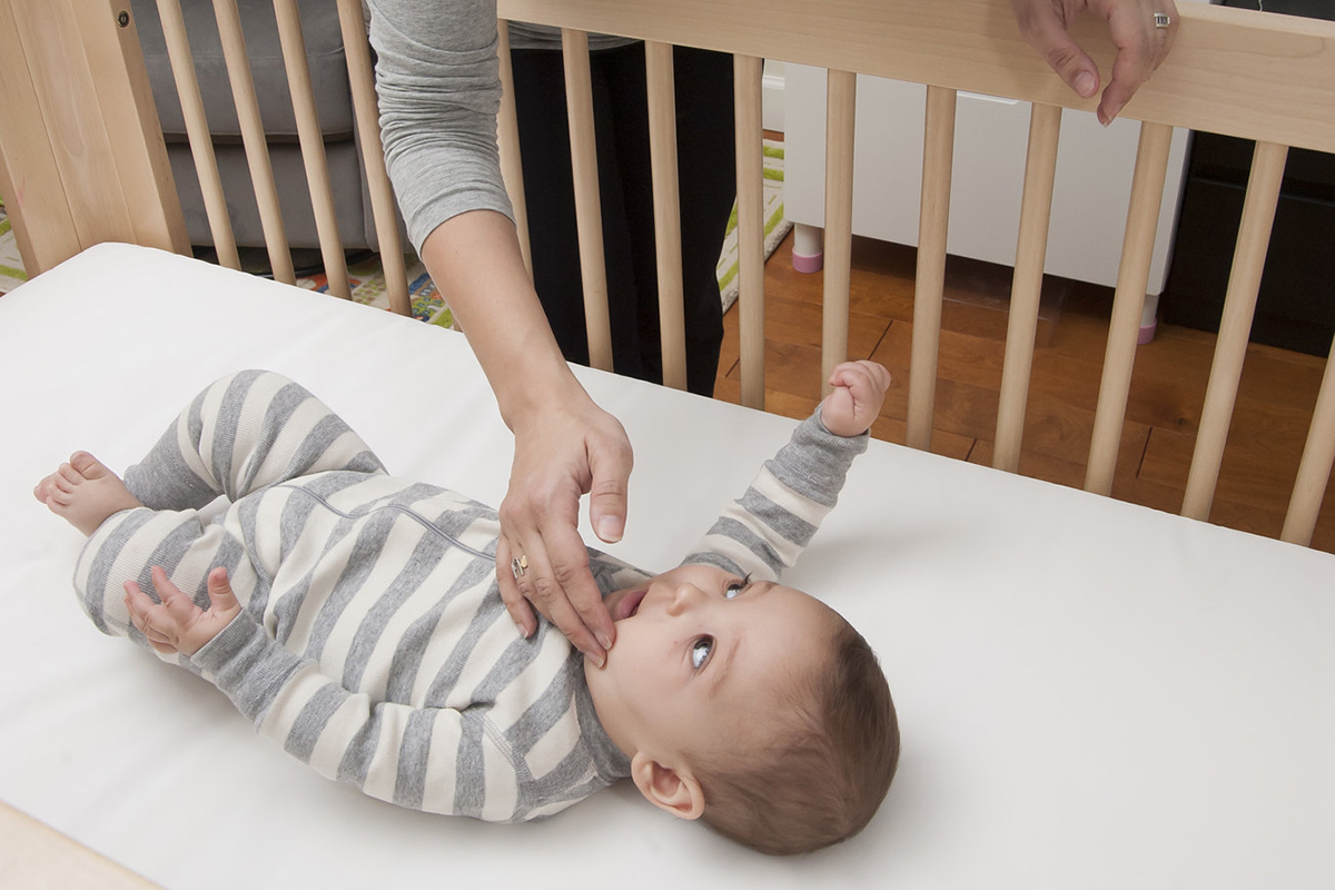 Mother putting baby to sleep in crib