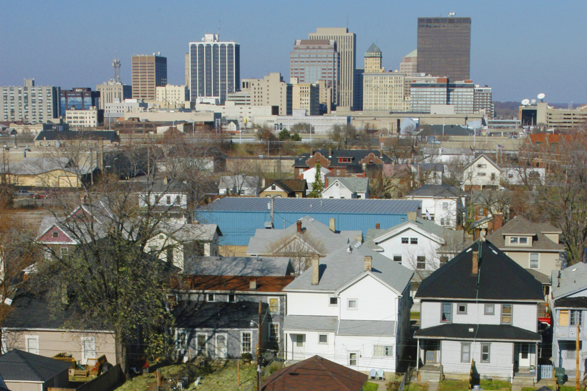 Cityscape with suburban homes in the foreground and a city skyline in the background.