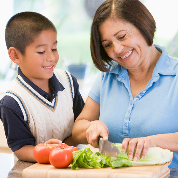 A mother and her son cutting vegetables.