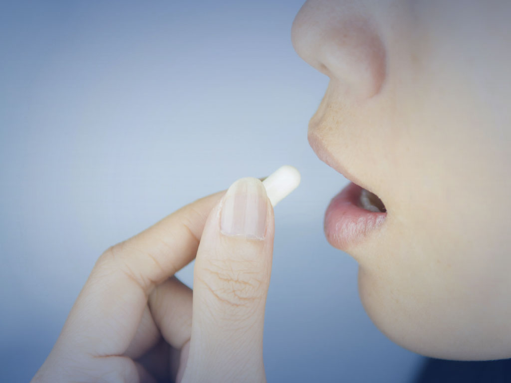 Photo of a woman taking a pill.