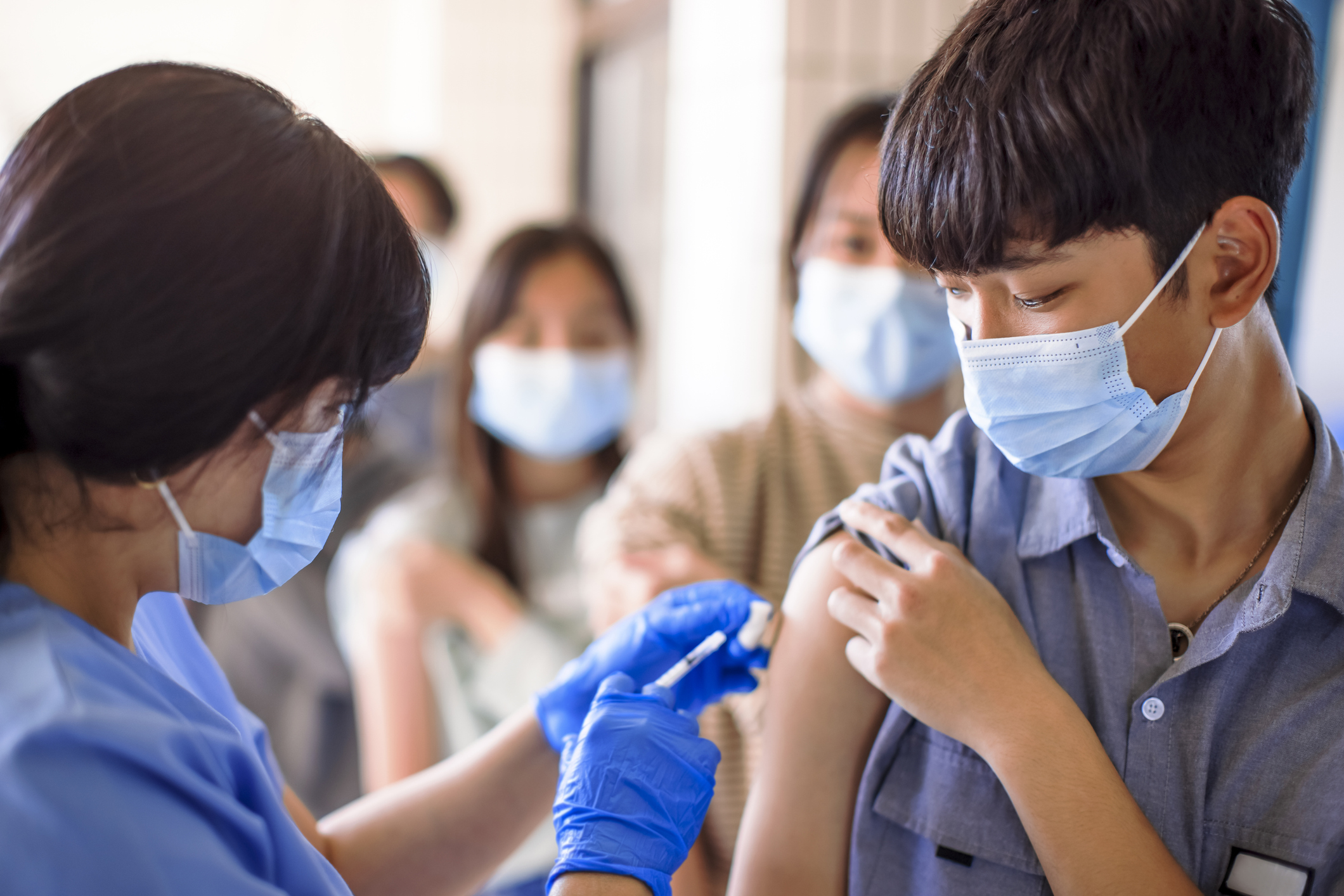 Doctor injecting vaccine for students in high school