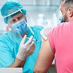 Medical technician administering vaccine to man's arm