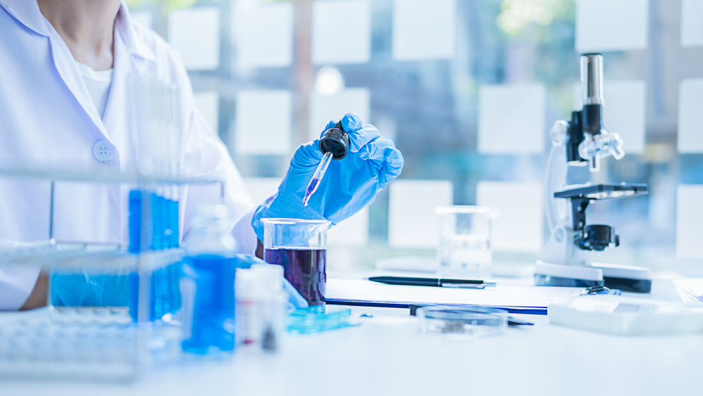 Medical or scientific researcher or man doctor looking at a test tube of clear solution in a laboratory