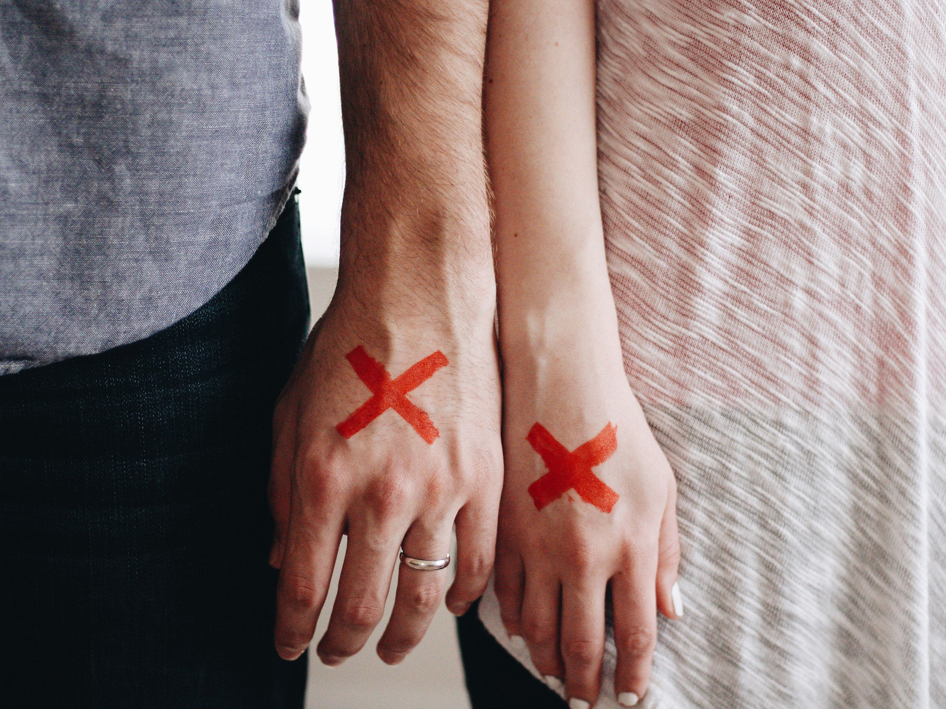 Two people’s hands marked with red X’s