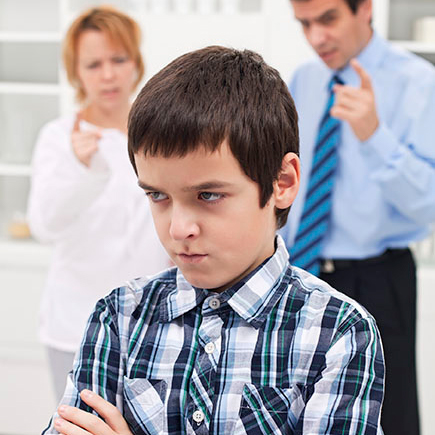 Parents lecturing their indignant son An indignant boy with his arms folded and back turned toward his parents, who are lecturing him.