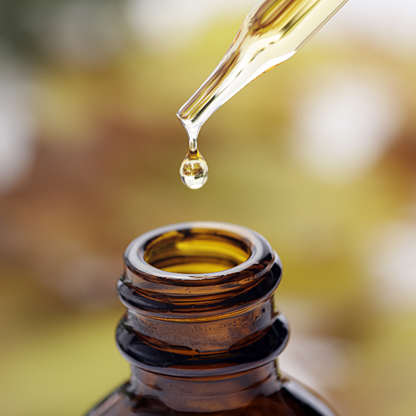 Essential oil dripping into a bottle from an eye dropper