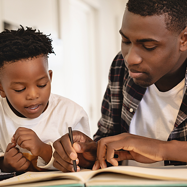 An African American father and son working on an activity book together