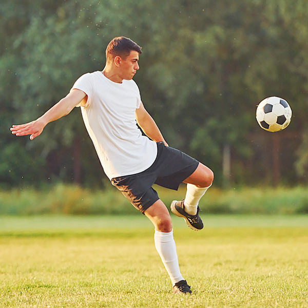 A man kicking a soccer ball on a field of grass