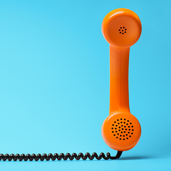 An orange telephone with a black coil cord on a blue background
