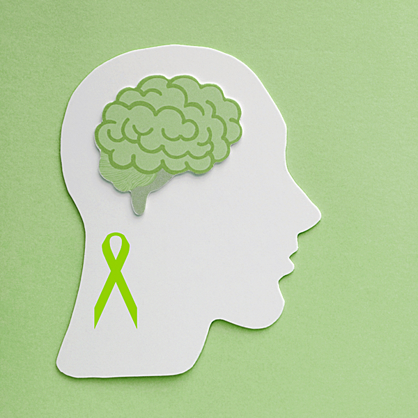 Paper cutouts of a green awareness ribbon and brain on a green background