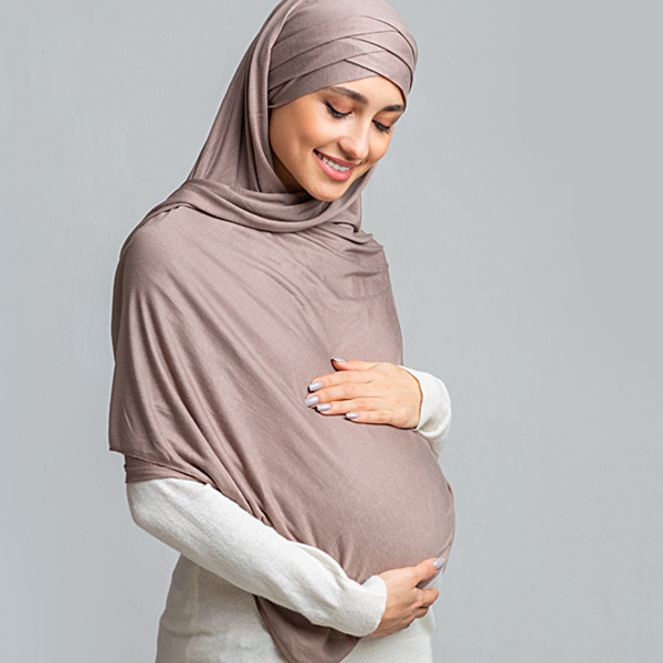 A pregnant woman holding and looking down at her stomach