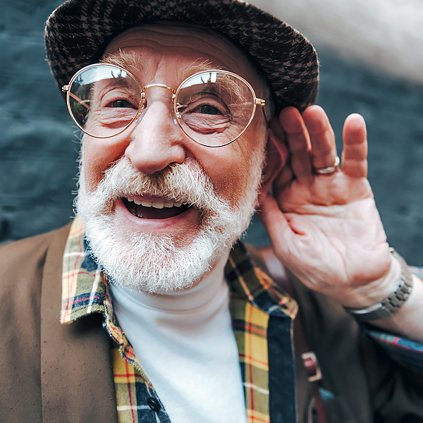 A senior man cupping his ear with his hand