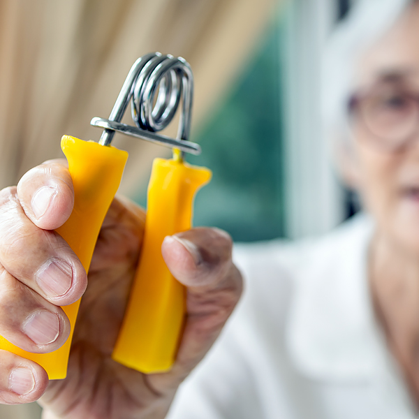 A close-up of a senior woman holding a hand gripper