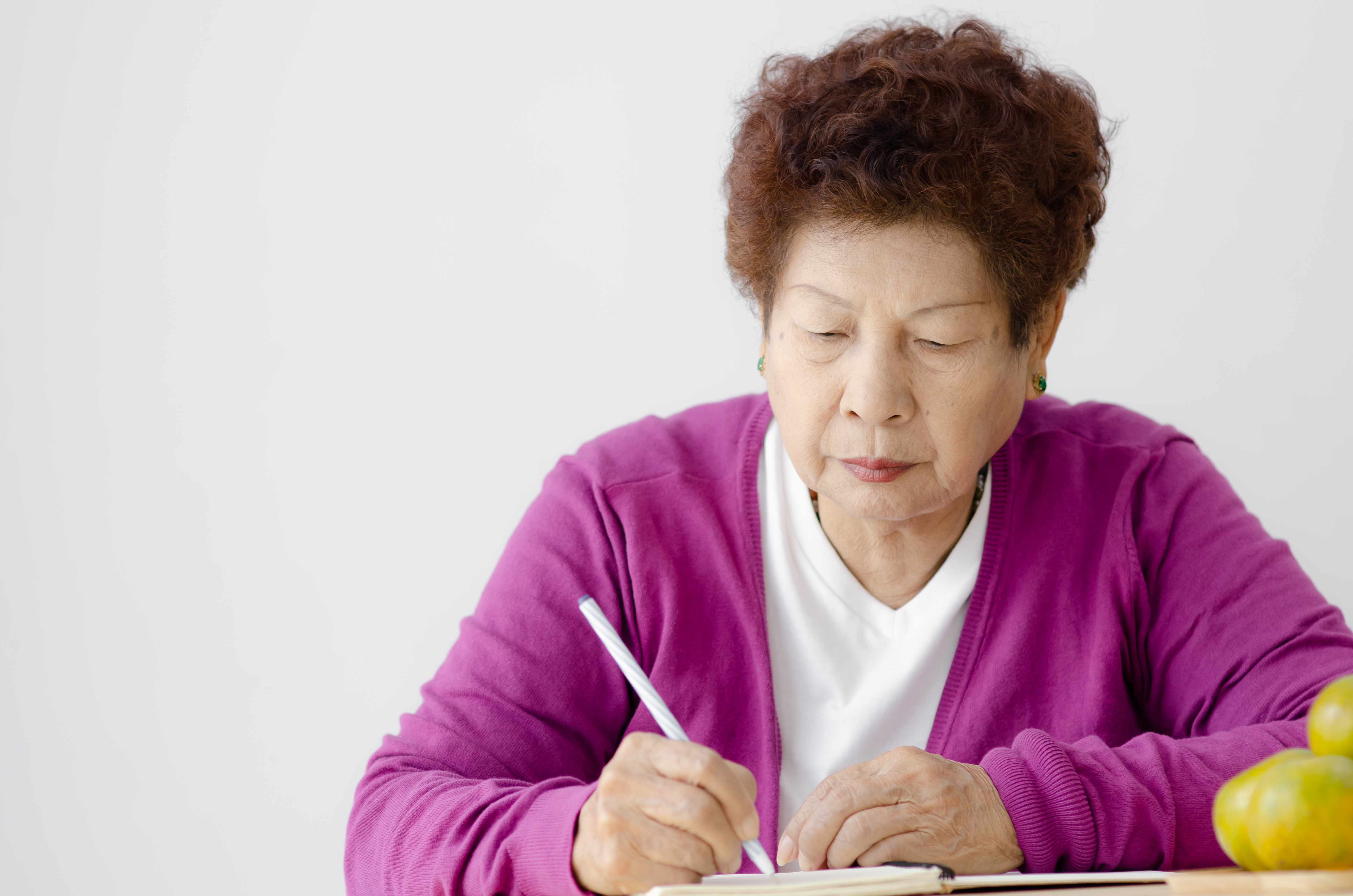 An Asian woman writing.