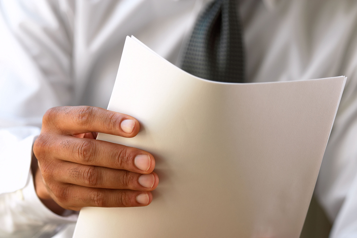 Close-up of a business man holding a stack of papers.