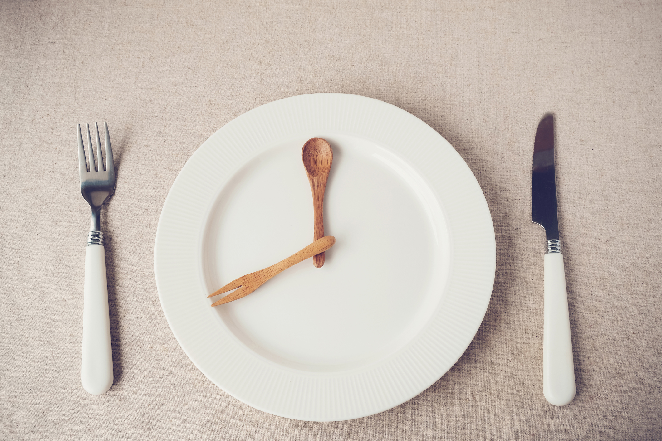 White plate with knife and fork representing hands of a clock.
