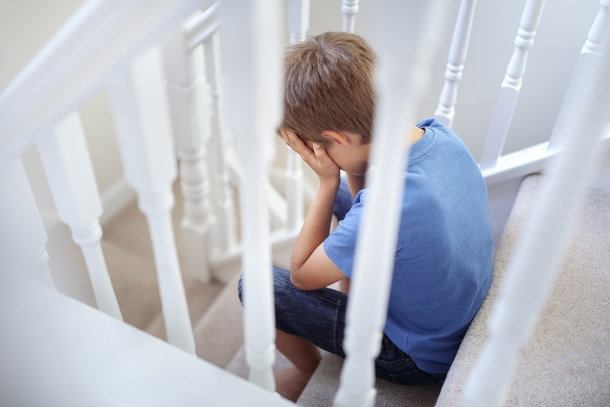 A sad young boy on the stairs