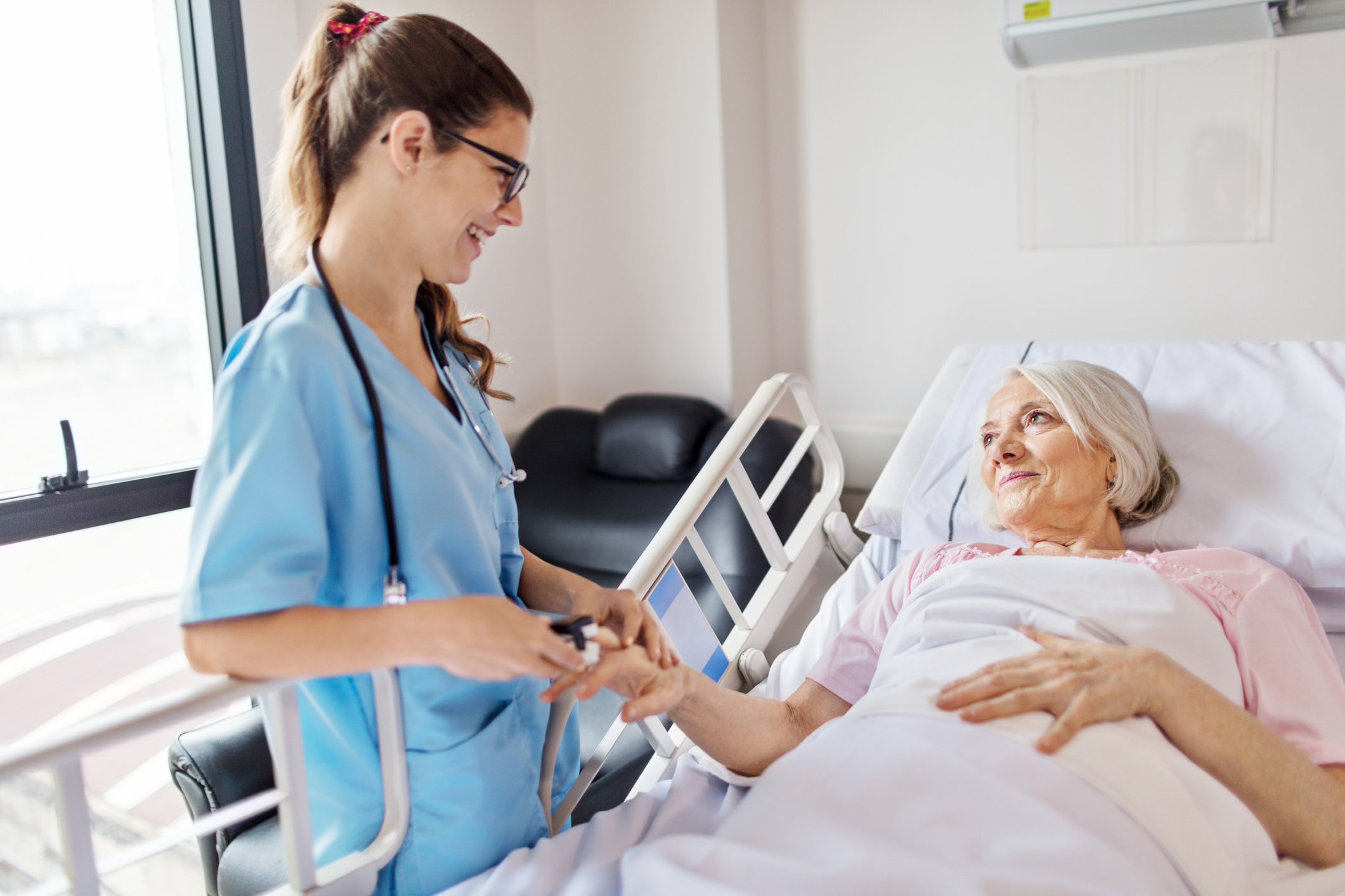 Nurse adjusting oxymeter on senior woman's finger