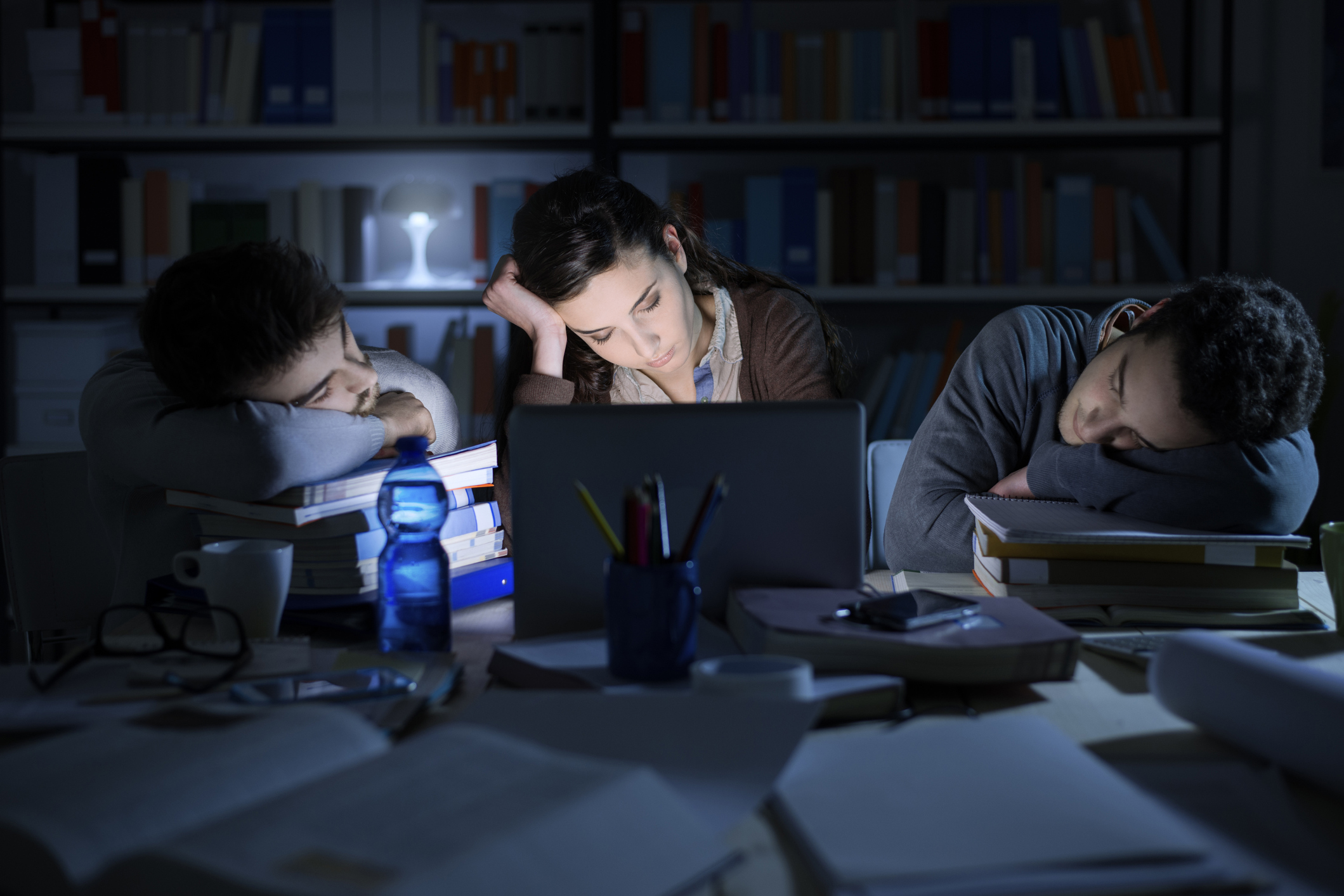 Tired students studying late at night, they are sleeping on the desktop and leaning on piles of books