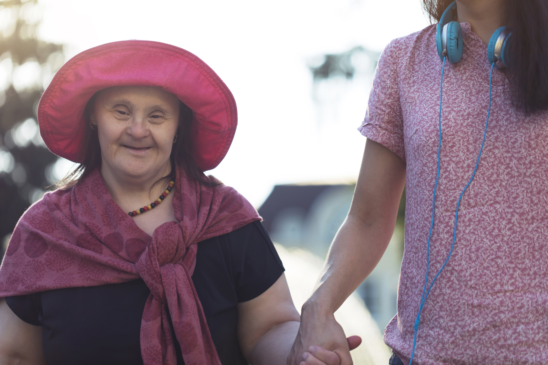 Woman with Down Syndrome and her young friend walking in a park.