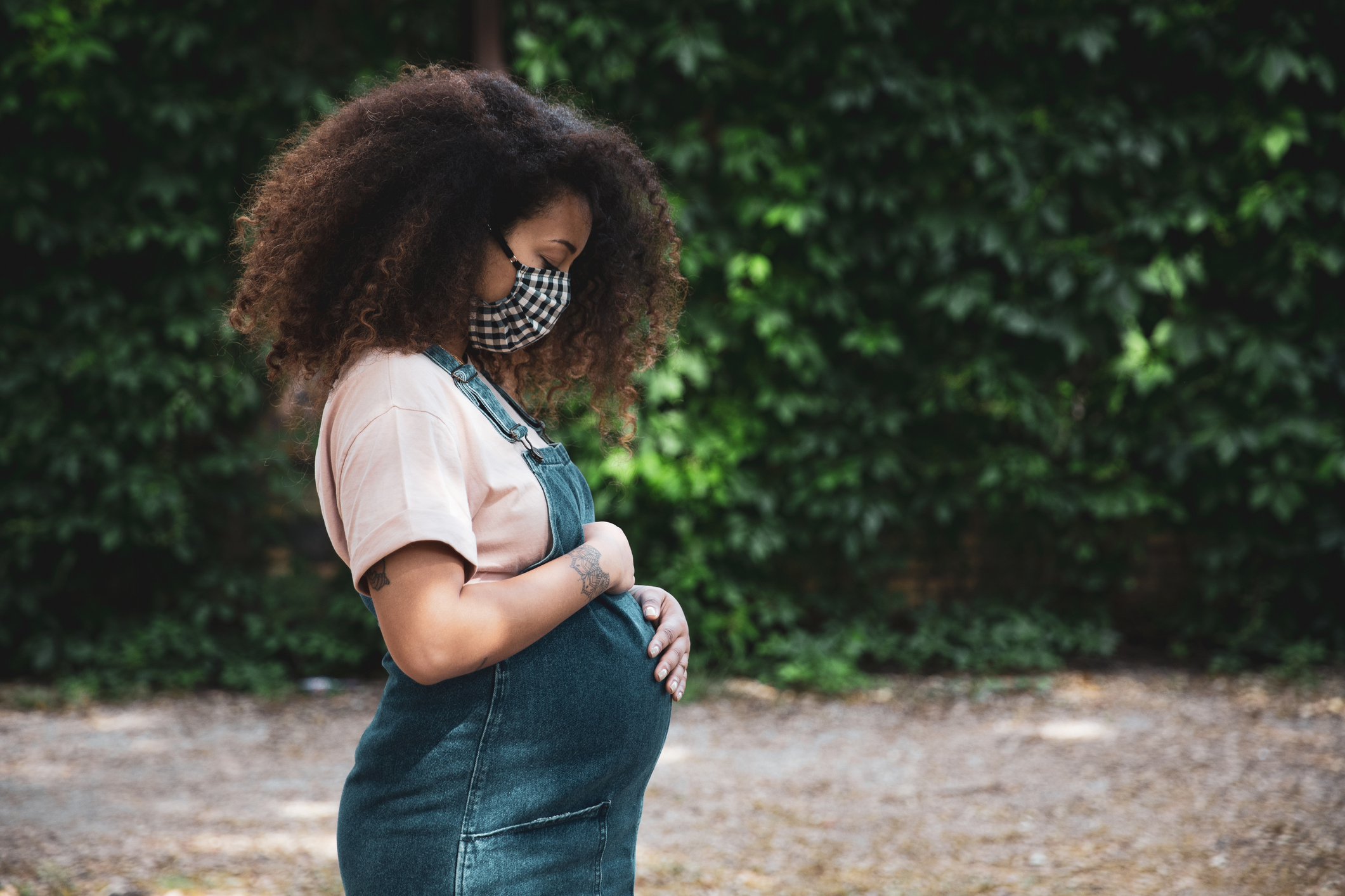 Pregnant afro hair woman in the city wearing a cloth protective mask - stock photo