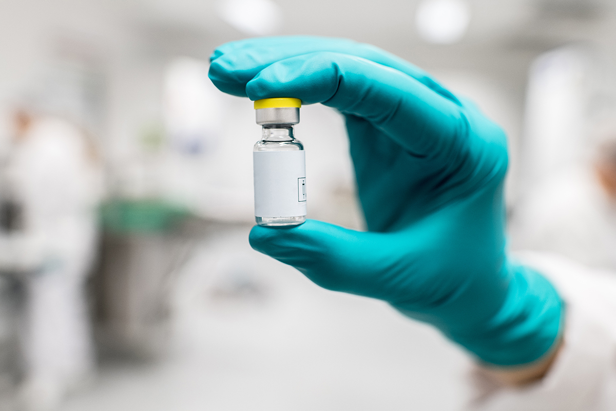 Gloved hand holding a vaccine vial. 