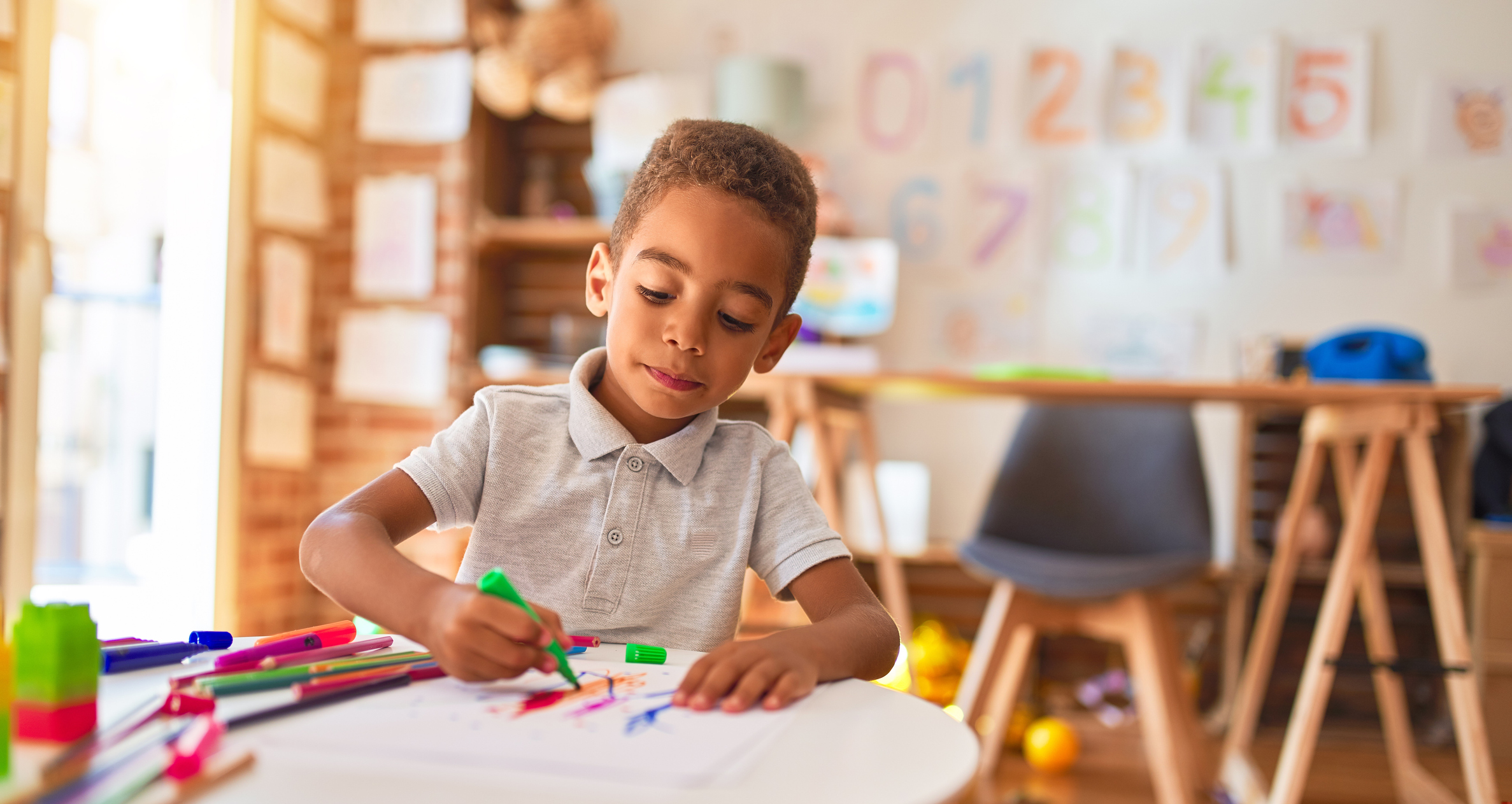 Beautiful african american toddler drawing using paper and marker pen at kindergarten - stock photo