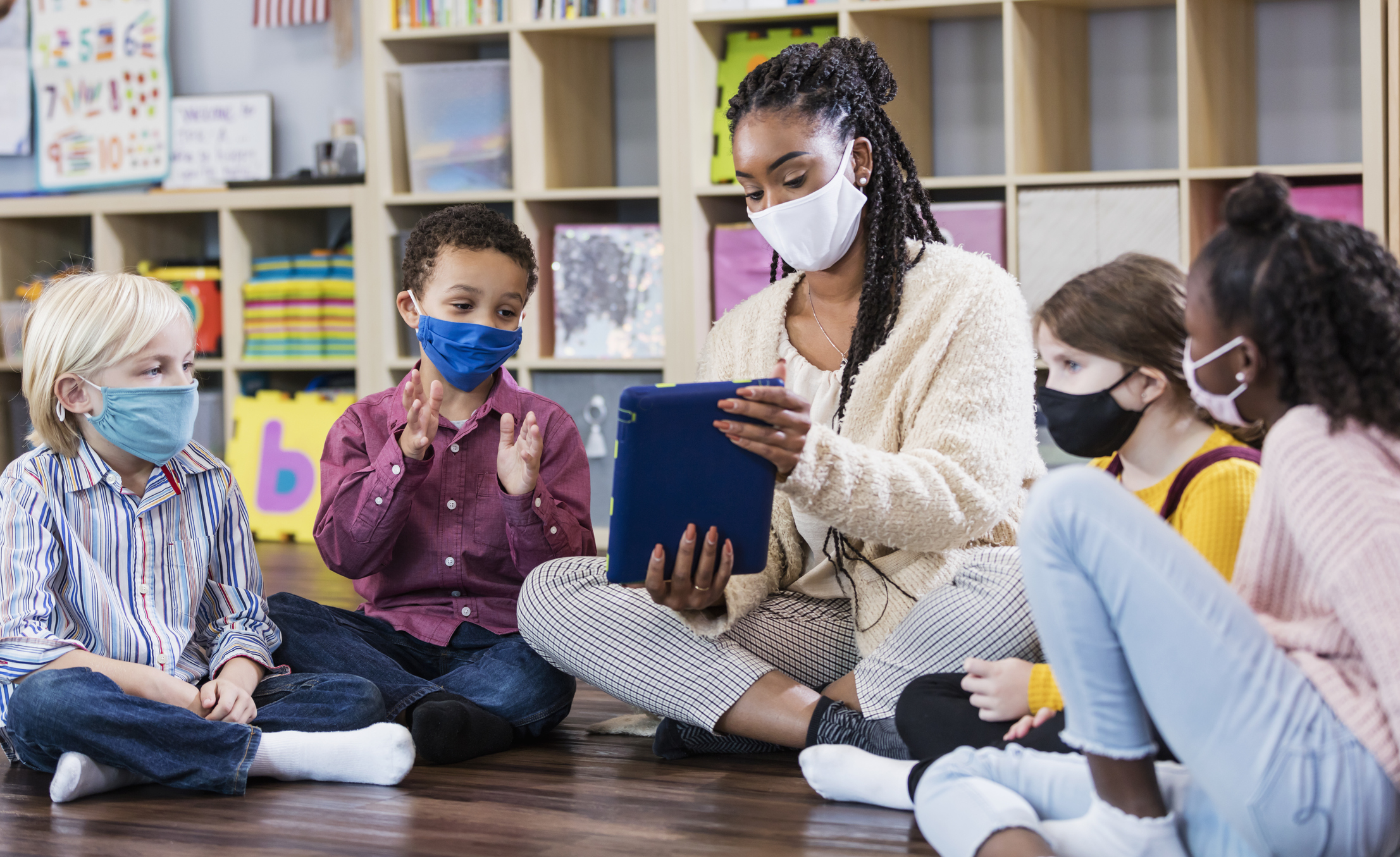 Preschool teacher, students in class, wearing masks - stock photo