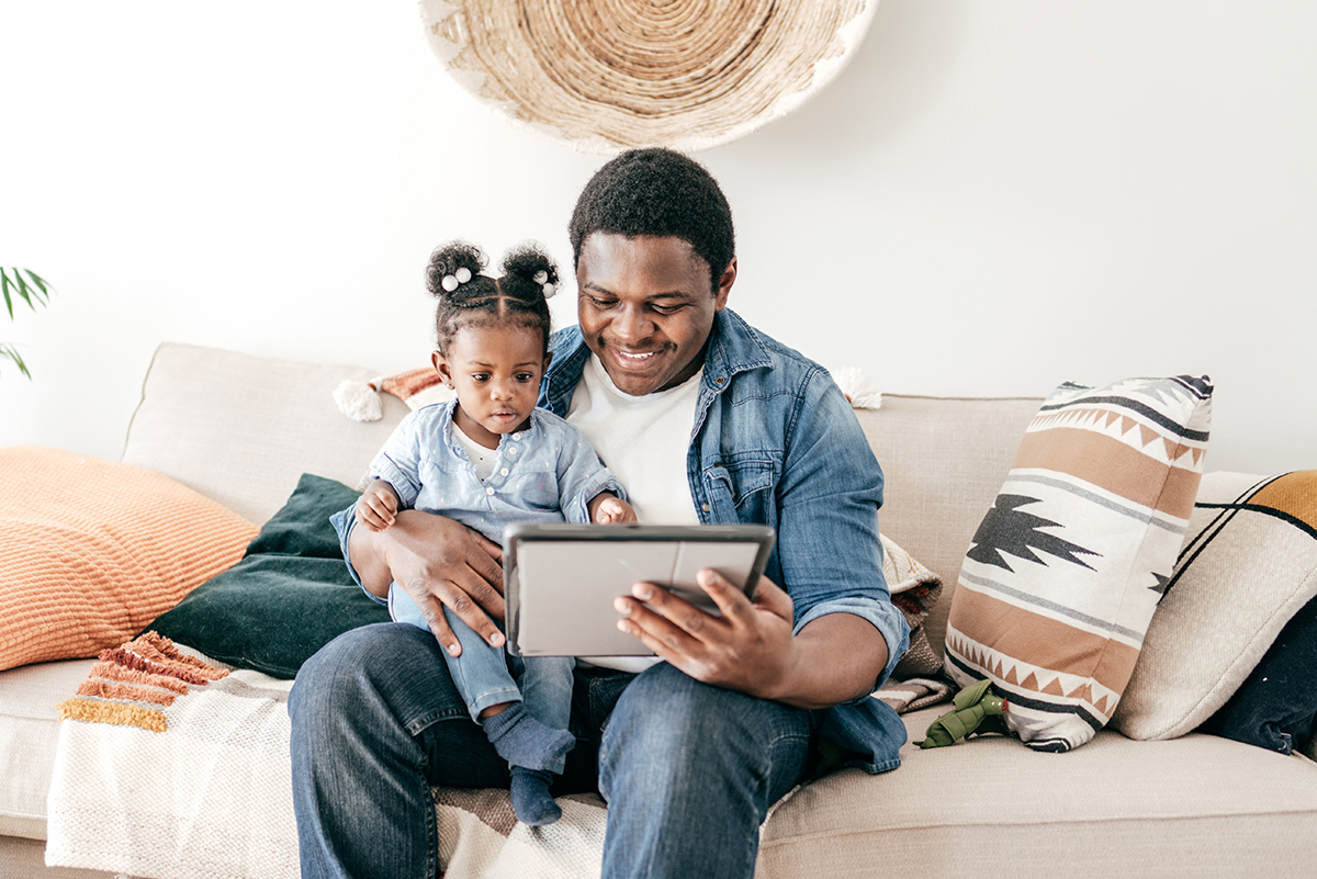 Father and toddler looking at an electronic tablet.
