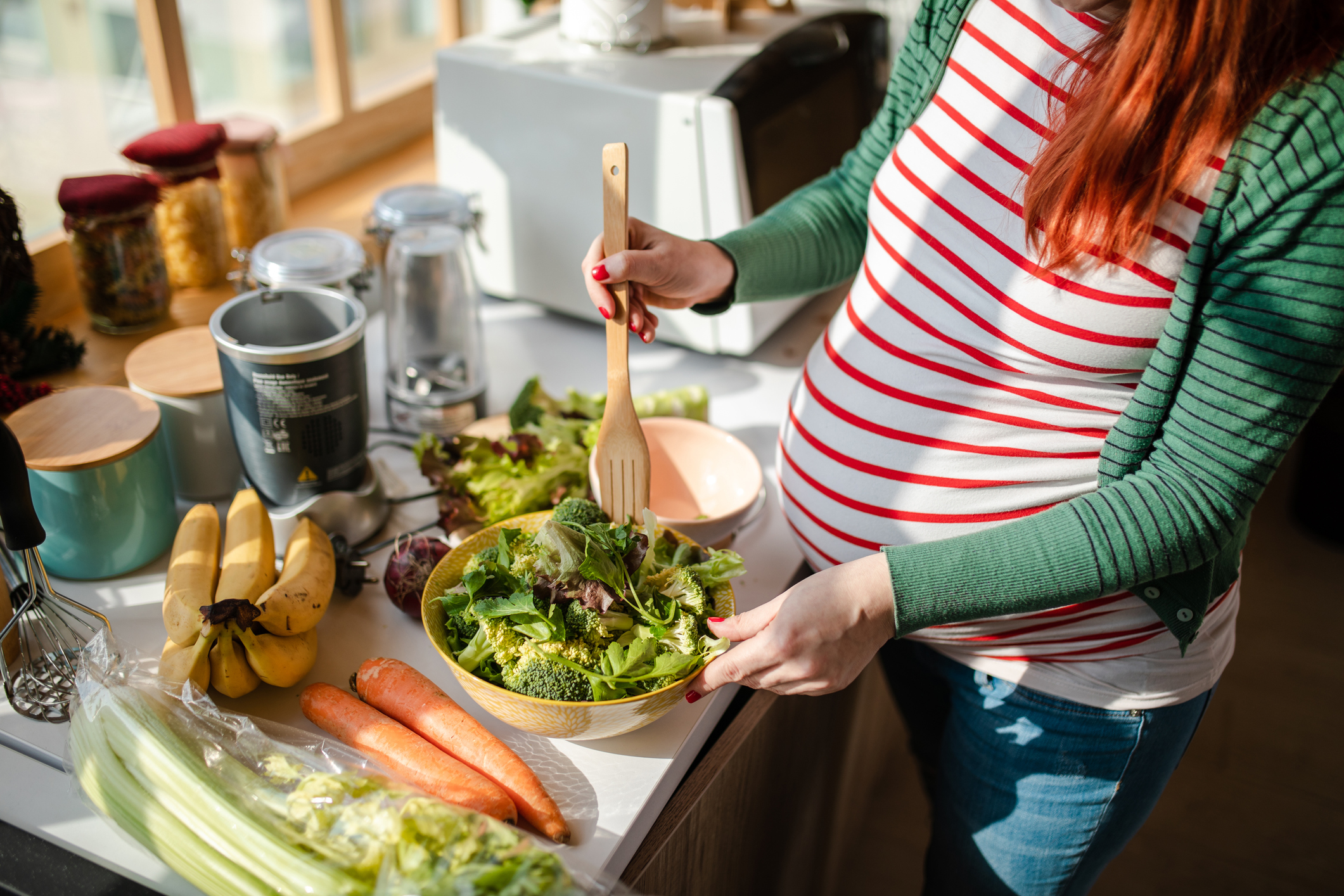 Healthy pregnant woman preapring a fresh organic salad for her breakfast - stock photo