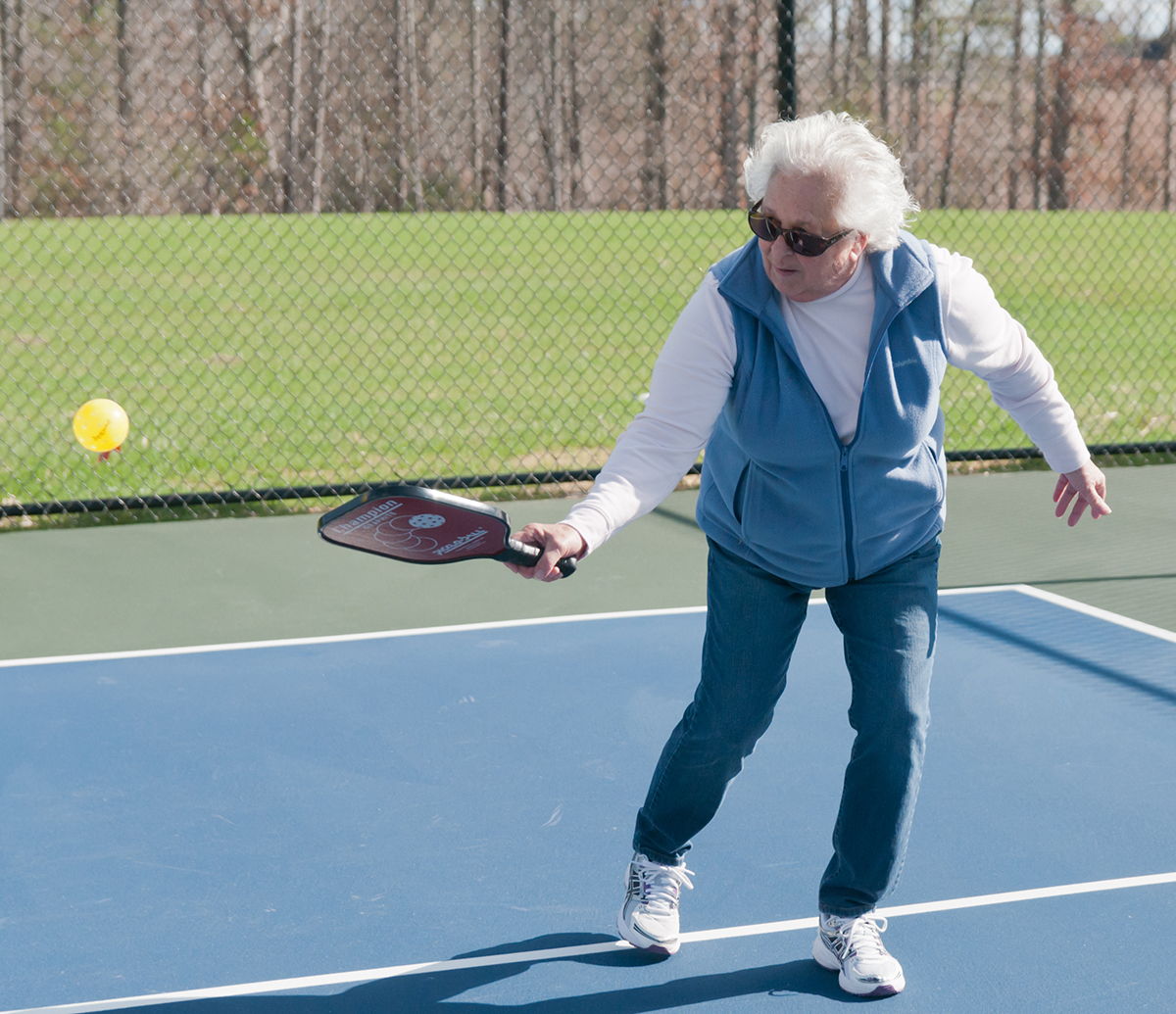 An older woman playing pickleball.