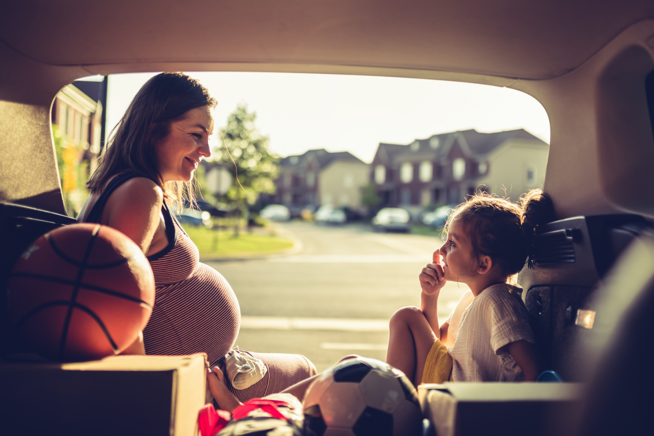 A pregnant woman sitting with child.