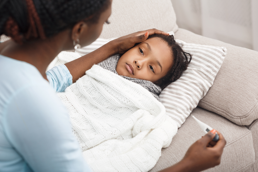 Fever Concept. Sick child in bed, mother holding thermometer, comforting poor girl