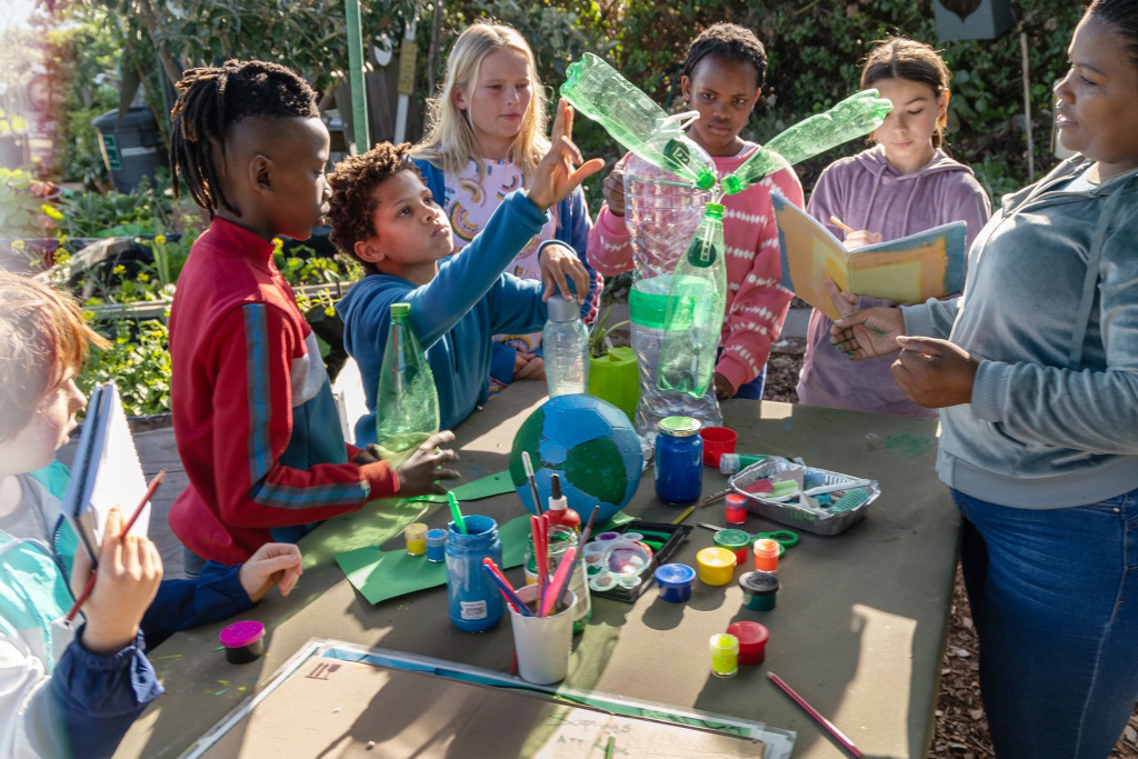  diverse group of six children making environmental art outdoors with an adult