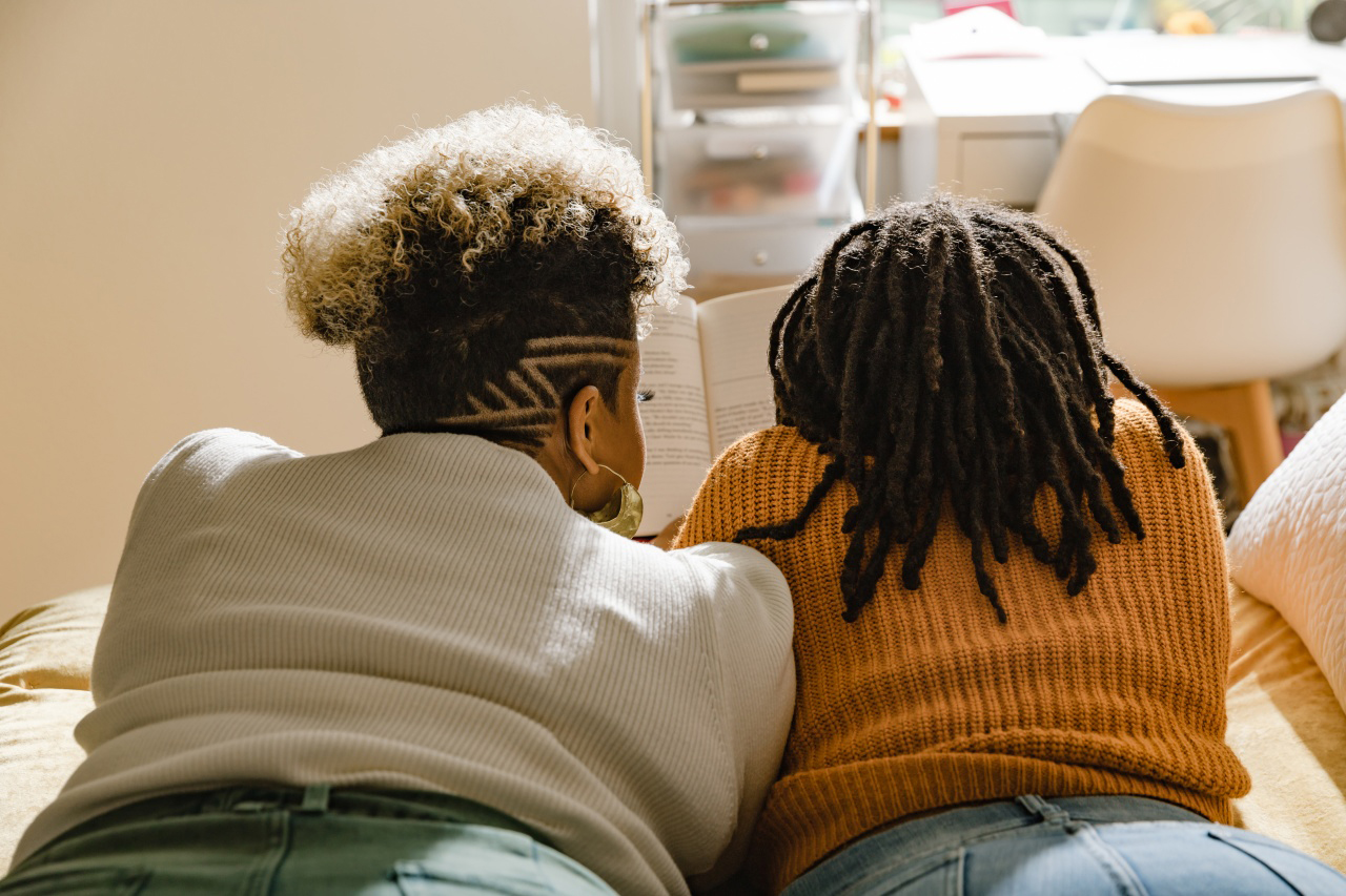 Two woman sitting a bed.