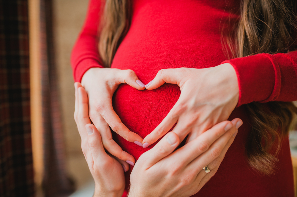 pregnancy concept - couple making a heart shape with their hands on the pregnant belly pregnancy concept - couple making a heart shape with their hands on the pregnant belly