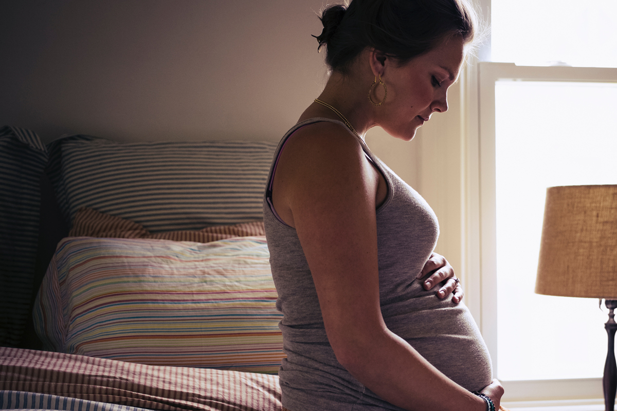 Image of a pregnant woman sitting on a bed