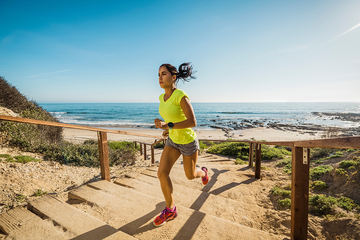 Image of a woman running up stairs near a beach