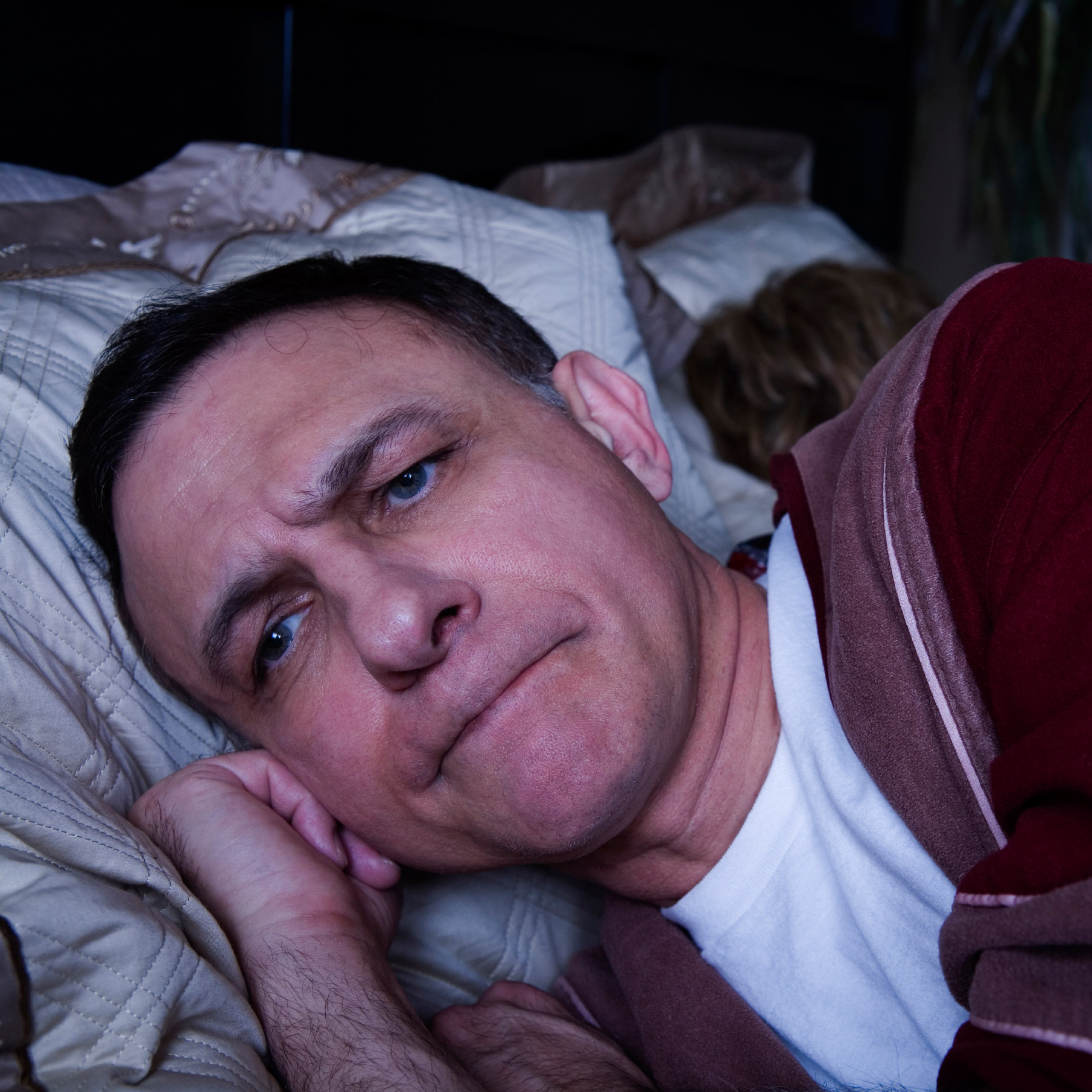 Photo of an angry man lying awake in bed - cropped
