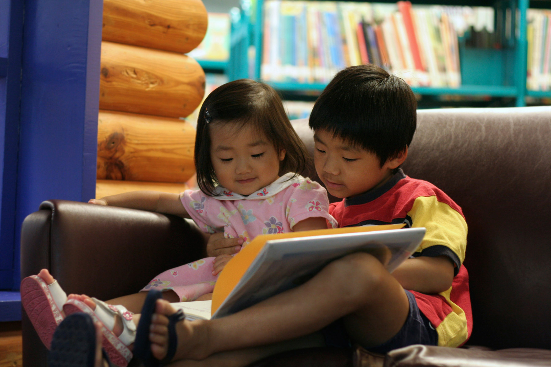 a photo of two preschool-age children looking at a book