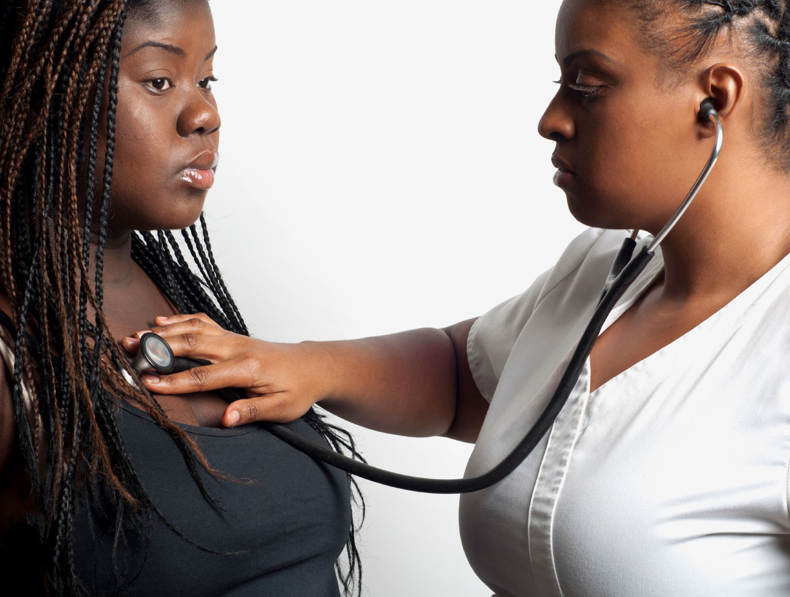 Doctor using a stethoscope to examine an overweight African-American woman.