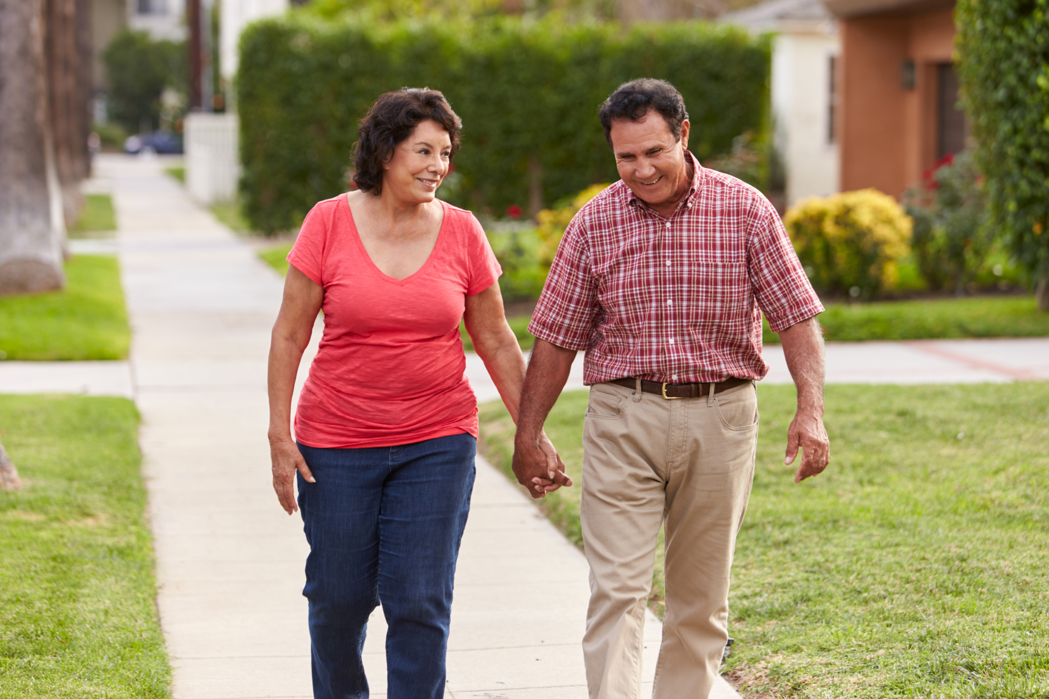 Senior Hispanic couple walking and holding hands on a sidewalk Senior Hispanic couple walking and holding hands on a sidewalk