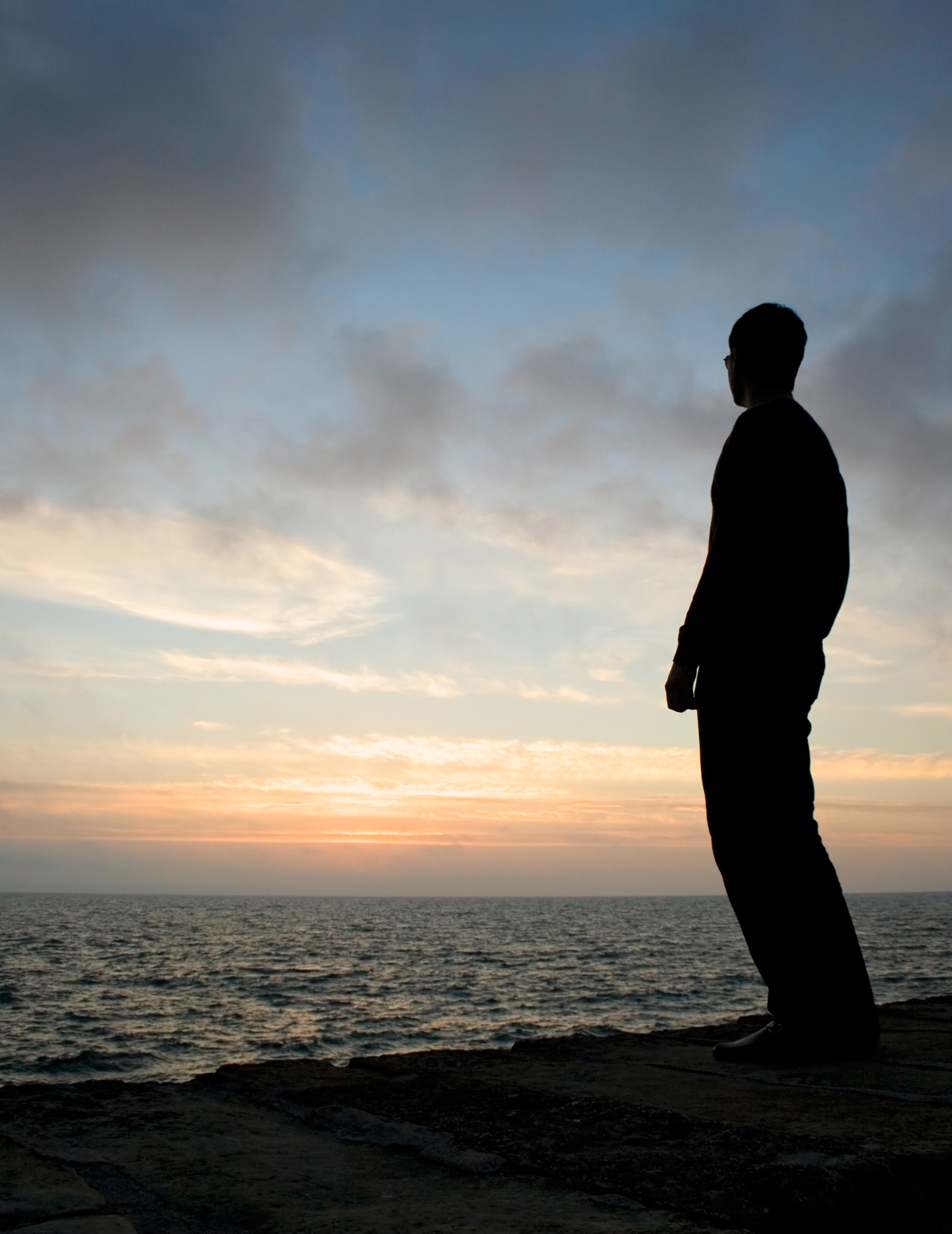 Silhouette of man watching sunrise off a pier