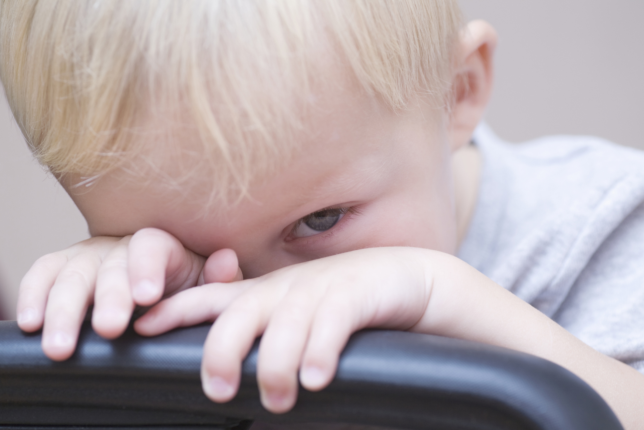 Blonde toddler peeking over a chair