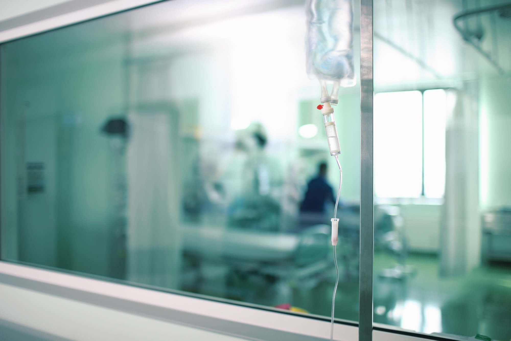Blurred photo of a hospital room through a corridor window